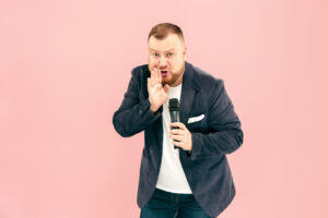 Come Affrontare La Paura Del Public Speaking 3 Giovane Con Microfono Sullo Spazio Rosa Che Porta Con Il Microfono 1